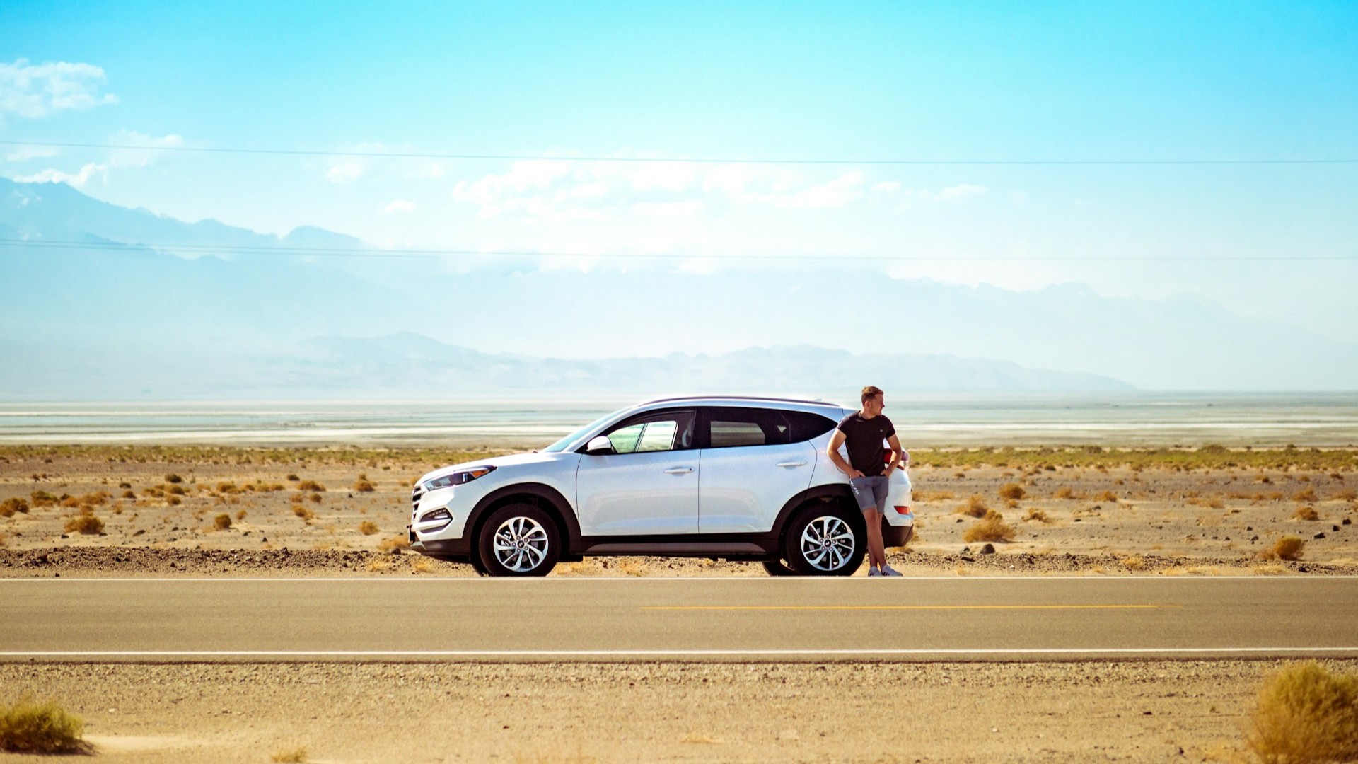 Auto stil langs lege weg in droge omgeving met bestuurder die wacht bij pech onderweg in afgelegen gebied