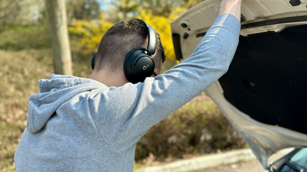 Bestuurder kijkt onder motorkap langs de weg bij pech onderweg met open kofferbak en veiligheidsbewust gedrag