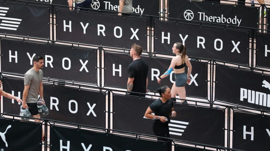 Deelnemers lopen tussen vakken tijdens een HYROX race, passend bij de groei van HYROX groeit snel in Nederland