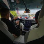 Bestuurder gebruikt scherm en smartphone in moderne auto waar digitale systemen auto-functionaliteiten aansturen