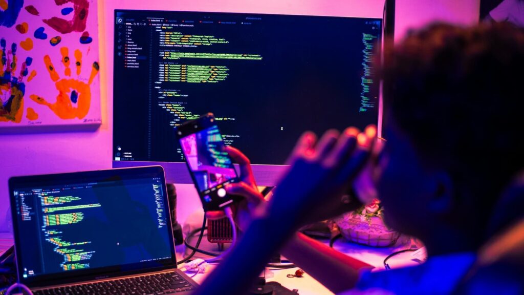 Programmeur gebruikt technologie in onderwijs met code op meerdere schermen